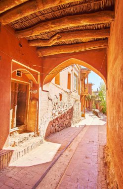 Eski günlük tavan ve kırmızı adobe duvarlar, Abyaneh Köyü, Iran evin altında dar boğaza yürürken.