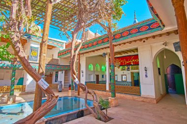 Abyaneh, Iran - 23 Ekim 2017: Eski üzüm asmaları süslenmiş Aşure bayrak ve afiş, dini yazıtlar üzerinde 23 Ekim Abyaneh içinde Jameh Camii'nin avlusundaki