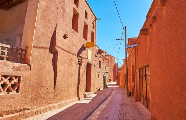 The narrow winding street, lined with old red adobe houses, traditional for Abyaneh village, Iran.