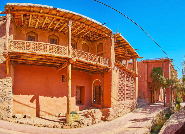 Panorama of the village street with old red adobe house, decorated with carved wooden elements, Abyaneh, Iran.