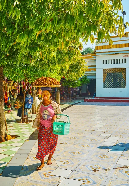 Sagaing, Myanmar - 21 Şubat 2018: Gülümseyen tembul fındık satıcı kafasına tepsi ile günü 21 Şubat Sagaing Kaunghmudaw Pagoda avlu, gölgeli sokak yürür.