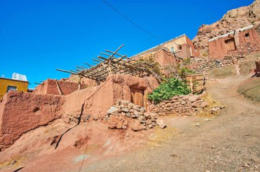Korunmuş ortaçağ evleri, kırmızı adobe, Abyaneh, Iran ile sarp dağ yamacı.