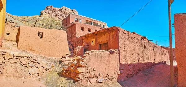 The shabby walls of medieval mud houses of Abyaneh village with the ruins of ancient fort on the mountain top, seen on the background, Iran.