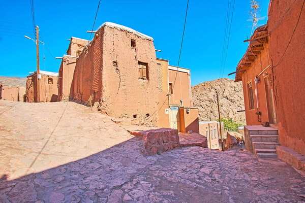 The medieval stone street branches into different directions with a view on the old adobe edifices in the middle, Abyaneh, Iran.