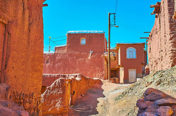 The scenic street of historic village with bright red clay buildings and narrow cwinding streets, Abyaneh, Iran.