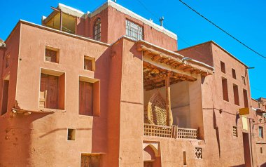 Abyaneh köy kırmızı adobe duvar ve Nahl ahşap yapı Aşure ritüel, terasta Iran ayakta için eski Camii cephe.