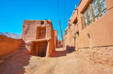 Eski günlerinden beri Karkas dağlarda, Abyaneh, Iran korunmuş adobe kırmızı-aşı boyası evleriyle eski tepelik sokakta yürüyorum.