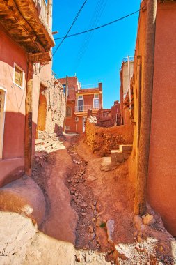 Kötü toprak yolun aşağı düşen yağmur ve eriyen kar yağışı, Abyaneh Köyü, Iran sırasında su akışları tarafından oluşturulan doğal oluk ile.