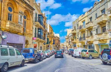 Mosta, Malta - 14 Haziran 2018: Il-Kbira street, 14 Haziran Mosta içinde eski konaklar, mağazalar ve kafeler, ile kaplı yoğun trafikte.