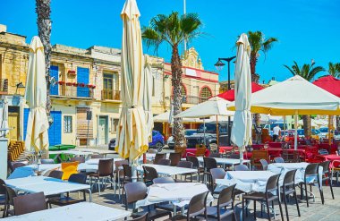 Rahat açık hava kafeleri Marsaxlokk shore Marina sunar lezzetli balık yemekler ve serinletici içecekler, Malta.