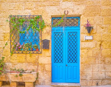 Mavi kapı ve pencere Malta Naxxar kasabasında konut binasının demir parmaklıklar arkasında kuyu geri