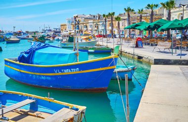Marsaxlokk, Malta - 18 Haziran 2018: sahil boyunca yürümek ve geleneksel luzzu tekneler, Marina yanındaki eski balıkçı tekneleri, Haziran 18 Marsaxlokk içinde demirleyen keyfini çıkarın.