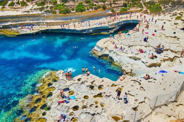 Marsaxlokk, Malta - 18 Haziran 2018: Tatilciler onların beach St Peter's havuzu, Delimara yarımadasının en güzel yerlerinden biri üzerinde 18 Haziran Marsaxlokk içinde iyi eğlenceler.