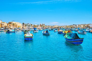 Marsaxlokk liman, üzerinde sallanan renkli luzzu teknelerin tam boyunca tembel yürüyüş zevk yavaşça dalgalar, Malta.