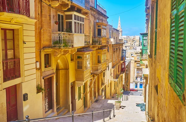 伝統的な木製のバルコニーやドア バレッタ マルタで飾られた 風光明媚なマルタの建造物と Vassali 通りに階段を歩く — ストック写真