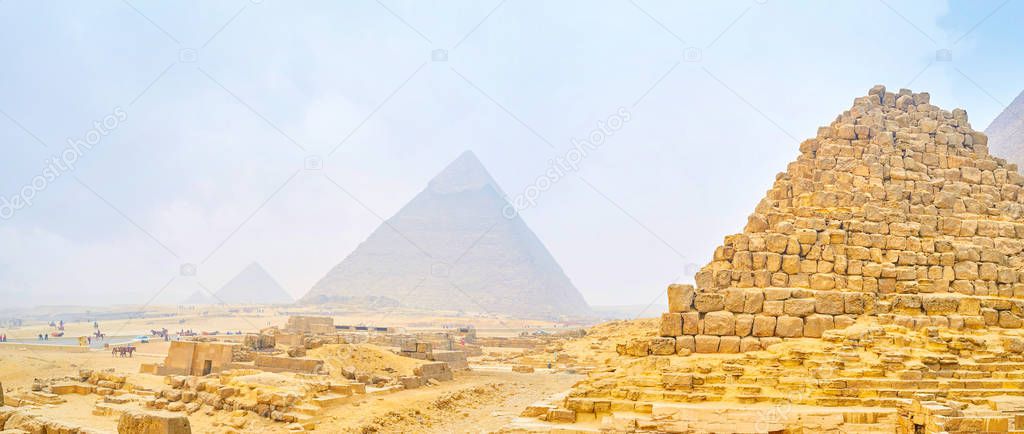 The foggy winter morning in Giza archaeological complex with ruins of ancient pyramids on the background, Egypt