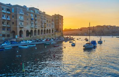 Senglea, Valletta duvarlar ve balıkçı tekneleri Vittoriosa Marina, Malta Ortaçağ yapılardır manzaralı Valletta Grand Harbour yukarıda gökyüzü ateşli.