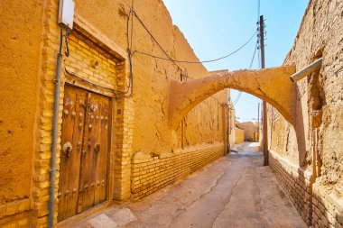 Ortaçağ ahşap kapı, dağılan adobe duvarlar, eğri kuche geçit ve dar yol, Yezd, Iran ile eski şehrin eski püskü sokak.