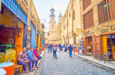 Cairo, Mısır - 20 Aralık 2017: 20 Aralık Kahire'de Ortaçağ yapıların, Manzaralı sokakta oturan küçük bir dükkanda diğer tüccarlar.