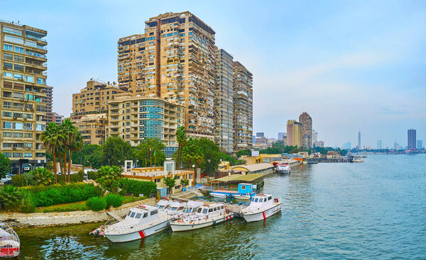 The riverside neighborhood of Giza with small port, lush green garden, ship restaurants and shabby residential quarters, Egypt.