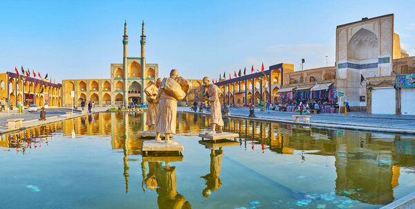 YAZD, IRAN - OCTOBER 18, 2017: Panorama of Amir Chakhmaq square with reflection of its landmarks (Hosseinieh, mosque and water carriers' sculpture) in waters of the fountain, on October 18 in Yazd