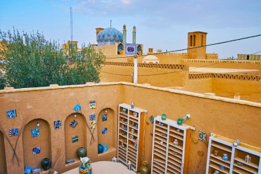Yazd, Iran - 18 Ekim 2017: Yazd sanat evi çatı üzerinde 18 Ekim Yazd içinde mahkeme El Sanatları Merkezi, adobe yapılardır ve görkemli Imamzadeh Seyyid Fathoddin rıza cami arka plan üzerinde bakan