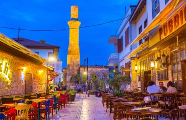 Antalya, Türkiye - 9 Mayıs 2017: akşam yemeği açık restoran Kaleiçi bölgesinde parlak ışıklar, Kesik Minare Camii (kırık minare) üzerinde bir görünüm ile 9 Mayıs Antalya zevk.