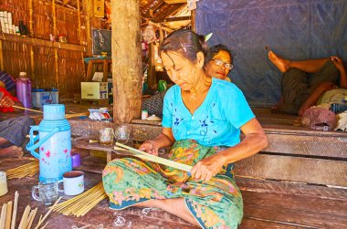 Chaung Tha, Myanmar - 1 Mart 2018: Birmanya kadın 1 Mart Chaung Tha içinde farklı şeyler - konik şapkalar, tabaklar, sepetler, duvar ve çatı panelleri, dokuma için bambu dar şeritler yapar.