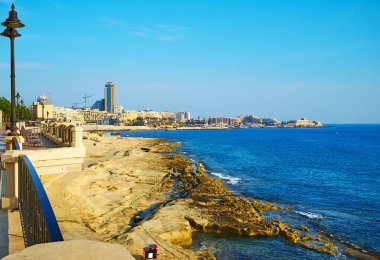 Sliema kayalık plaj Tower Road boyunca uzanan, St Julian's modern mahalle arka planda görülür, Malta.