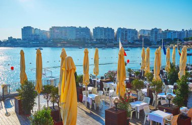 St Julians, Malta - 20 Haziran 2018: Rahat açık hava teras sürgünler coast koyunda Restoran güç tekneler ve modern yapıların Sliema, 20 Haziran St Julians manzaralı.