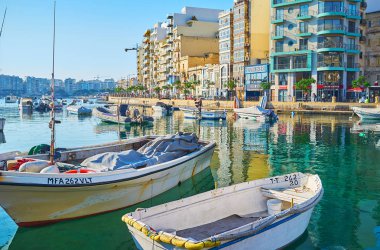 St Julians, Malta - 20 Haziran 2018: Spinola Bay yürümek ve sallanan tekneler izlemek ve su yüzeyinde yansıma üzerinde 20 Haziran St Julians için açık.