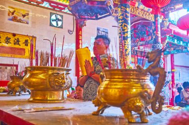 Yangon, Myanmar - 17 Şubat 2018: Genç adam bir sunak Kheng Hock Keong (Qingfu) tapınak tütsü sopa, üzerinde 17 Şubat olarak Yangon fuming ile büyük vazo arkasında bulunan dua ediyor.