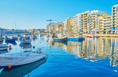 St Julians, Malta - 20 Haziran 2018: Spinola Bay harbor sakin sularına demirli renkli tekneler ve modern binalar onun kıyısında 20 Haziran St Julians yansıtmak.