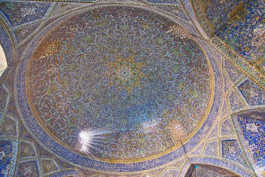 ISFAHAN, IRAN - OCTOBER 21, 2017: Richly decorated dome of Seyed Mosque with stunning tile pattern, Quranic calligraphy, muqarnas and Persian screens, providing the daylight, on October 21 in Isfahan.