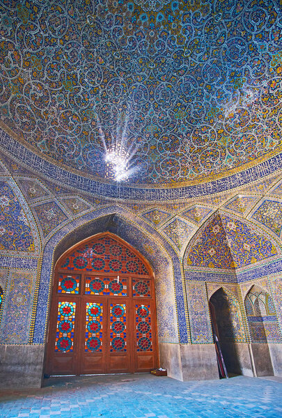 ISFAHAN, IRAN - OCTOBER 21, 2017: Interior of Seyed Mosque with stained-glass door, Persian screen, providing sun rays and rich tile decoration on walls and dome, on October 21 in Isfahan.