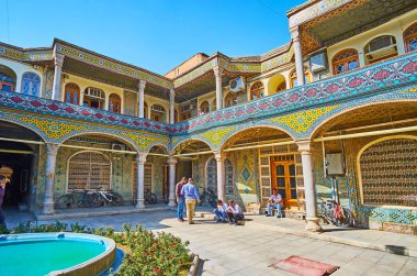 ISFAHAN, IRAN - OCTOBER 21, 2017: The scenic courtyard of Timche-ye Malek of Grand (Soltani) Bazaar with ornate verandas and fountain in the middle, on October 21 in Isfahan. clipart