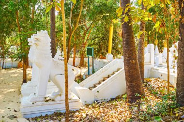 Shwethalyaung Buddha Tapınağı gölgeli bahçe keyfini ve pagoda, Bago, Myanmar koruyan doğal Ortaçağ chinthe leogrpyphs heykelleri seyretmek