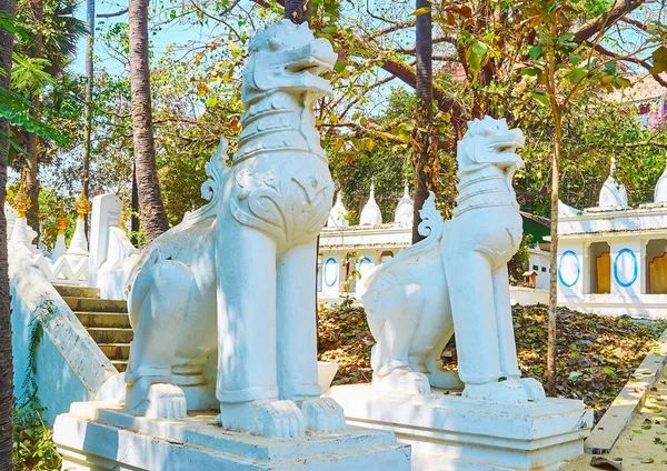 The white statues of chinthe (leogryphs, royal lions) in garden a the entrance to Shwethalyaung Buddha Temple, Bago, Myanmar.