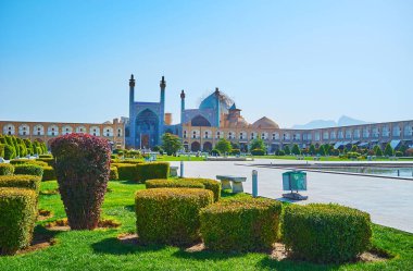 Süslü portal ve büyük gök kubbesi Nakş-ı Cihan Meydanı, Isfahan, Iran süs Bahçe kesilmiş çalılıkların arkasında tarihsel şah (Royal, Imam) Camii.