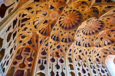 ISFAHAN, IRAN - OCTOBER 21, 2017: The walls and complex dome of Music Hall of Ali Qapu palace are covered with different shaped adornaments in Tong Borie technique, on October 21 in Isfahan. clipart