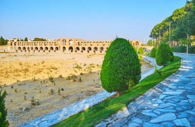 Sulu çim ve kesilmiş mazı Zayanderud nehir Ayineh hane Bulvarı, köprü arka plan, Isfahan, Iran görülür Khaju'ndaki bankanın boyunca ağaçlar kurumuş çizgi.