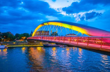 Romantik akşam yürüyüş boyunca Vistula Nehri setin manzaralı cazip aydınlatma baba Bernatek yaya köprüsü, Krakow, Polonya