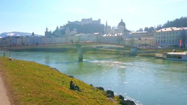 エリザベート ザルツァッハ川の堤防はザルツブルグで 日にホーエン ザルツブルク城塞と歴史的な街の建造物を望むピクニックに最適な場所 ザルツブルク オーストリア 2019 — ストック動画