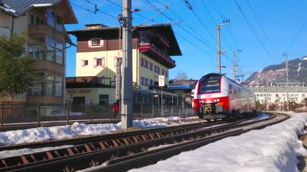 モダンな赤い電車ツェル オーストリア 2019 日ツェル ゼーのドライブに沿って古い雪の降る街の建造物 — ストック動画