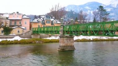 Hızlı akan Traun Nehri boyunca eski köprünün görünümü, arka planda onun banka ve karlı Alpleri üzerinde doğal konaklar, Bad Ischl, Salzkammergut, Avusturya.  