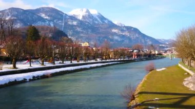Traun nehrinin Embankments parkları ile kaplıdır, gölgeli banka hala Snowbound ve güneşli bir yeşil çim sahiptir; Katrin Dağı arka planda görülür, Bad Ischl, Salzkammergut, Avusturya.