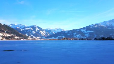 Buzla kaplı ve kayalık Alpleri ile çevrili Zeller See 'nin manzarasını sunan göl kenarındaki Elisabeth parkın keyfini çıkarın, Zell See, Avusturya.