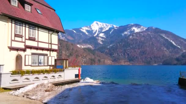 歴史的な邸宅 湖とアルプスの斜面の深い青い海 ザルツカマーグート オーストリアの景色を望むセントギルゲンの湖畔の通り — ストック動画