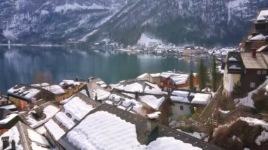 Eski Hallstatt 'ın yoğun bir şekilde bulunan karlı çatıları, duman ile birlikte, yavaşça bacalar ve Hallstattersee Gölü 'nden çıkıyor, Rocky Dachstein Alpleri, Salzkammergut, Avusturya.