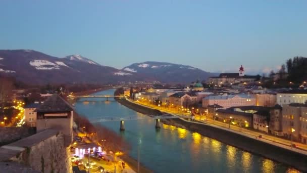 萨尔茨堡浪漫的晚间城市景观 在萨尔茨堡河畔 城市桥梁 历史街区和阿尔卑斯山的背景 奥地利昏暗的灯光 — 图库视频影像